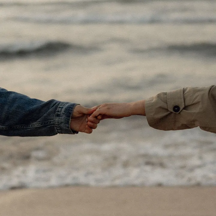 Two people holding hands at the edge of the sea